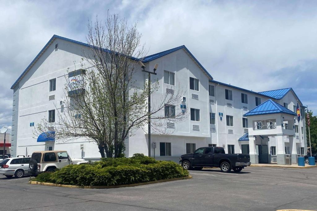 un grand bâtiment blanc avec des voitures garées dans un parking dans l'établissement Baymont by Wyndham Loveland - Fort Collins Area, à Loveland