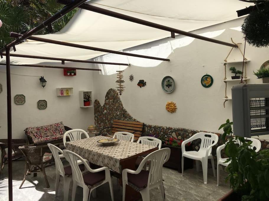 eine Terrasse mit einem Tisch, Stühlen und einem Sofa in der Unterkunft Il mare a 100 M da casa con ampio giardino in Torregrotta
