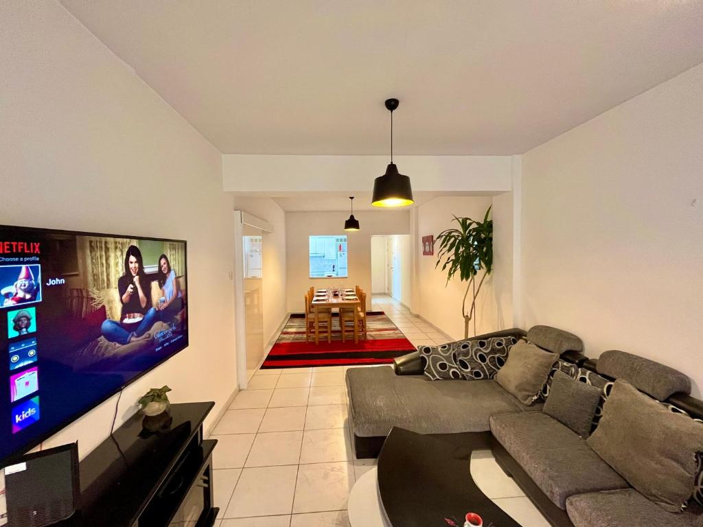 ein Wohnzimmer mit einem Sofa und einem Flachbild-TV in der Unterkunft Two Bedroom City Seaside Apartment in Limassol