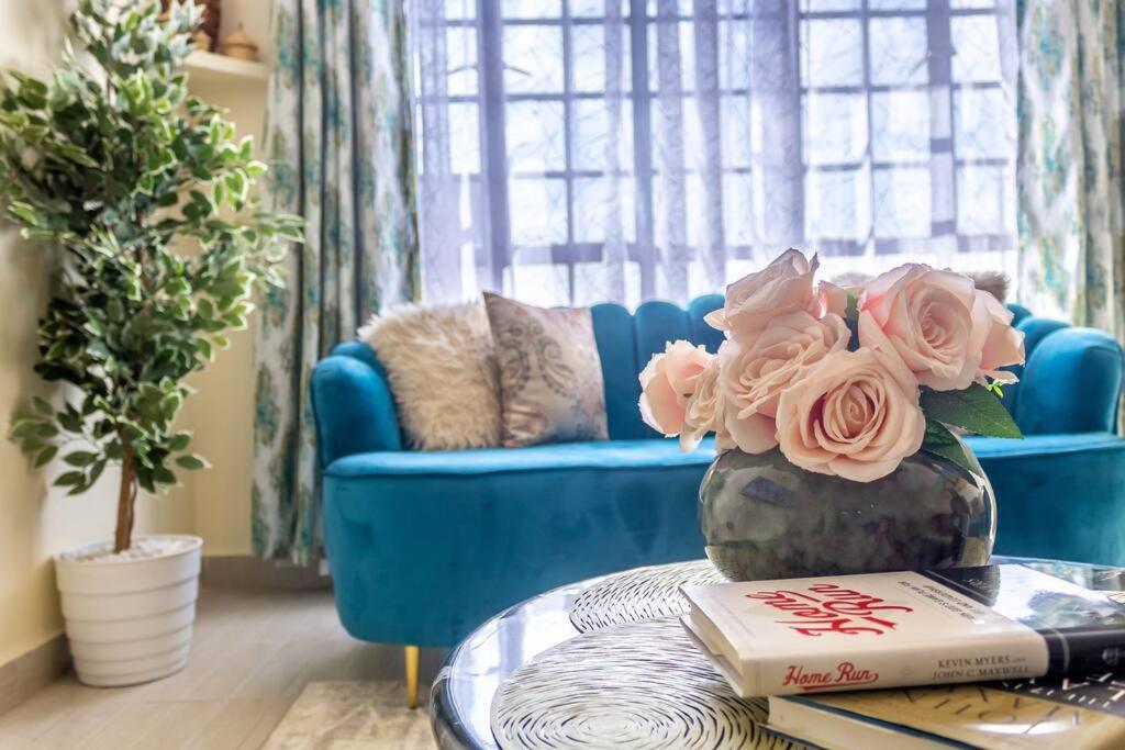 a living room with a blue couch and a table with a book at Quzuri Homestay nearJKIA SGR NRB Kenya in Syokimau