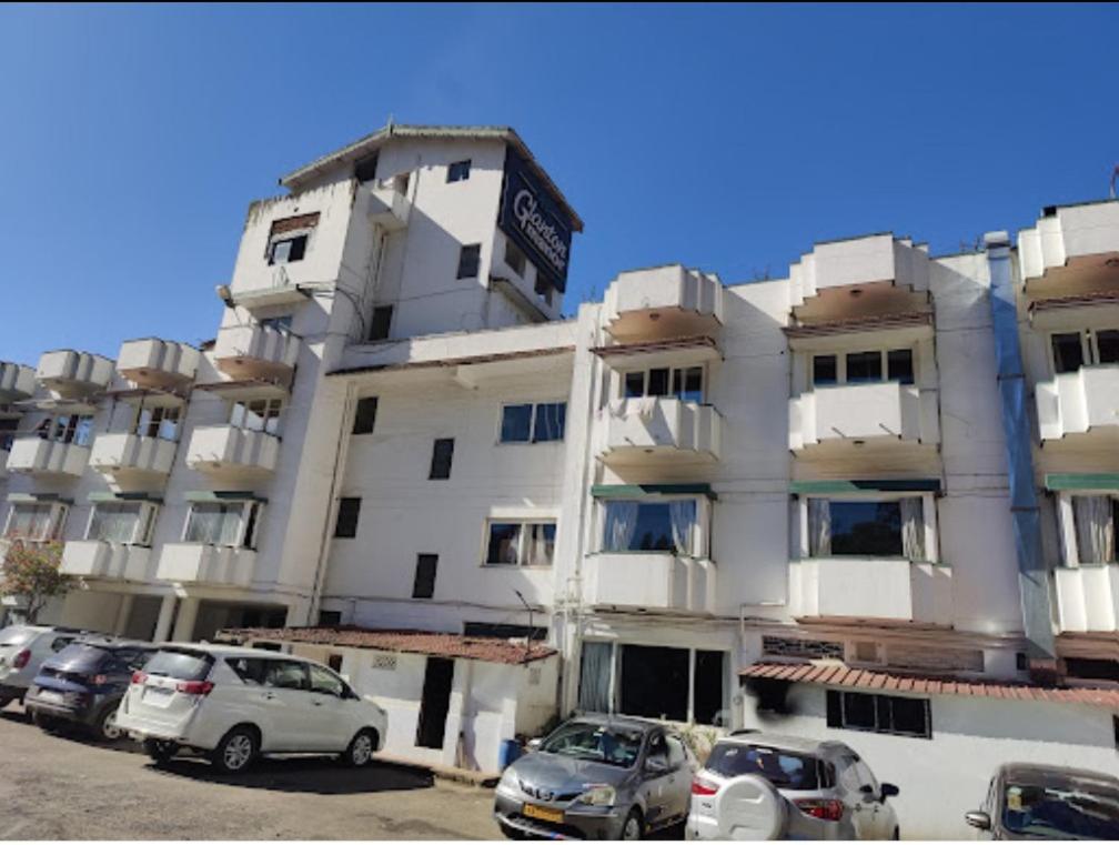 a large white building with cars parked in front of it at Hotel Glanton Manor in Ooty