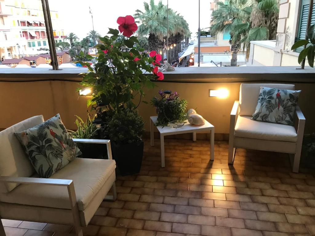 uma varanda com duas cadeiras, uma mesa e flores em Appartamento Piazza Anco Marzio em Lido di Ostia