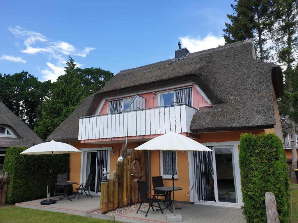 a house with a thatched roof with tables and umbrellas at Buhne IV OG in Wieck