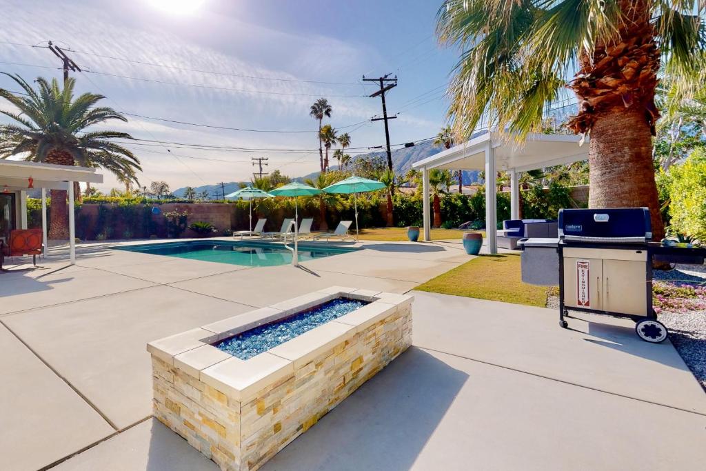 un patio trasero con una piscina y una palmera en Desert Willow Mod Permit# 5268 en Palm Springs