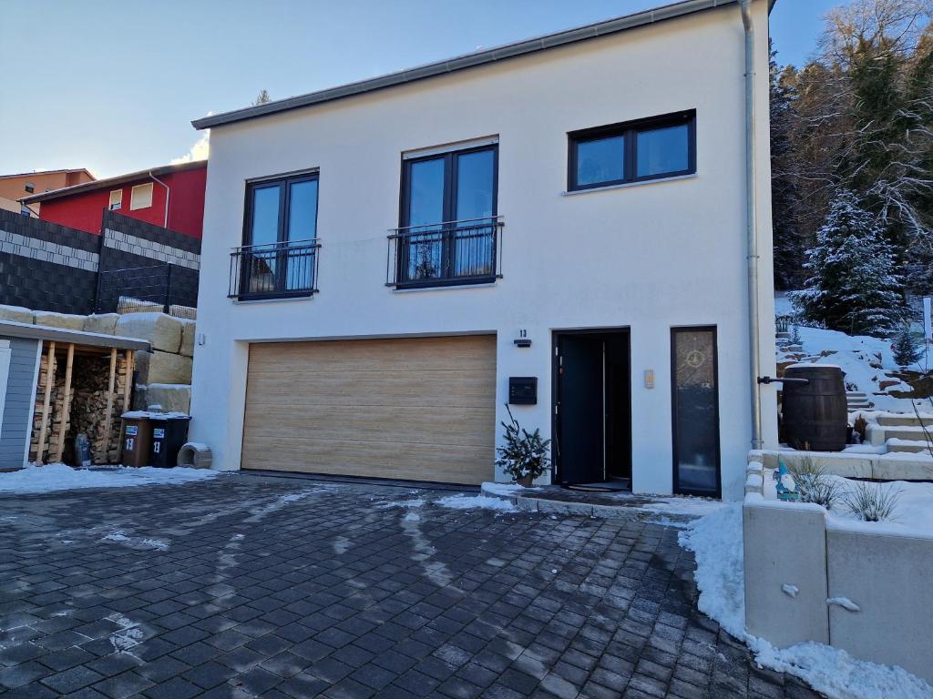 a white house with a garage in the snow at Apartment im Nordschwarzwald in Unterreichenbach