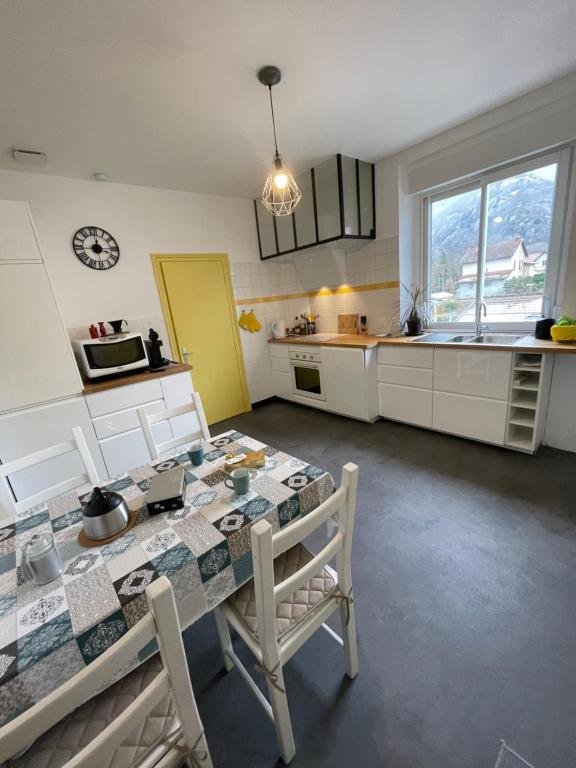 une cuisine avec une table, des chaises et une horloge murale dans l'établissement Appartement Tarascon sur Ariège, à Tarascon-sur-Ariège