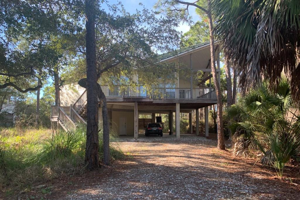 uma casa com varanda no meio das árvores em Seminole Wind em St. George Island