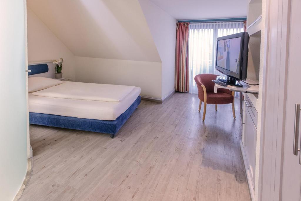 a bedroom with a bed and a desk with a television at Romantik Hotel Gasthaus Rottner in Nuremberg