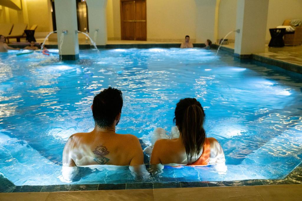 un hombre y una mujer sentados en una piscina en Buona Vitta Gramado Resort & Spa by Gramado Parks, en Gramado