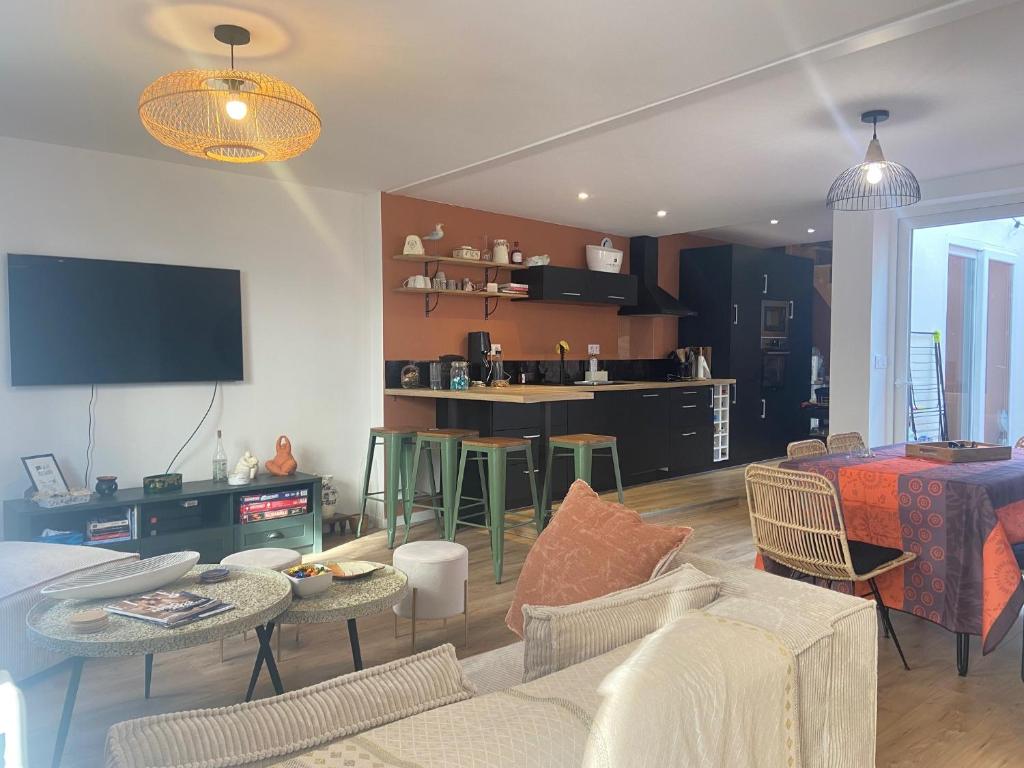 sala de estar con sofá, mesas y cocina en Belle maison de vacances avec patio - pour 6 pers - à deux pas de la grande plage et du centre ville en Les Sables-dʼOlonne