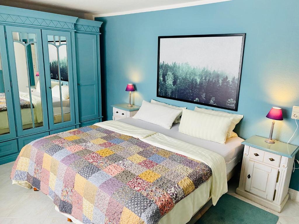 Dormitorio azul con cama con colcha colorida en FeWo hohetanne1 en Großbreitenbach