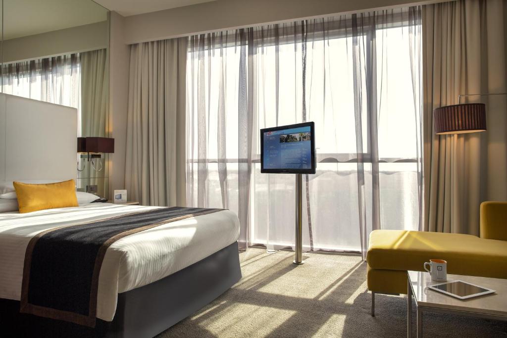 a hotel room with a bed and a flat screen tv at Centro Sharjah in Sharjah