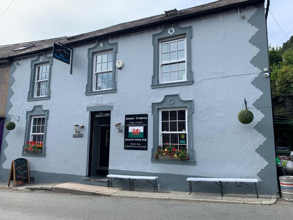 a white building with two benches in front of it at The Slaters Arms Corris in Machynlleth