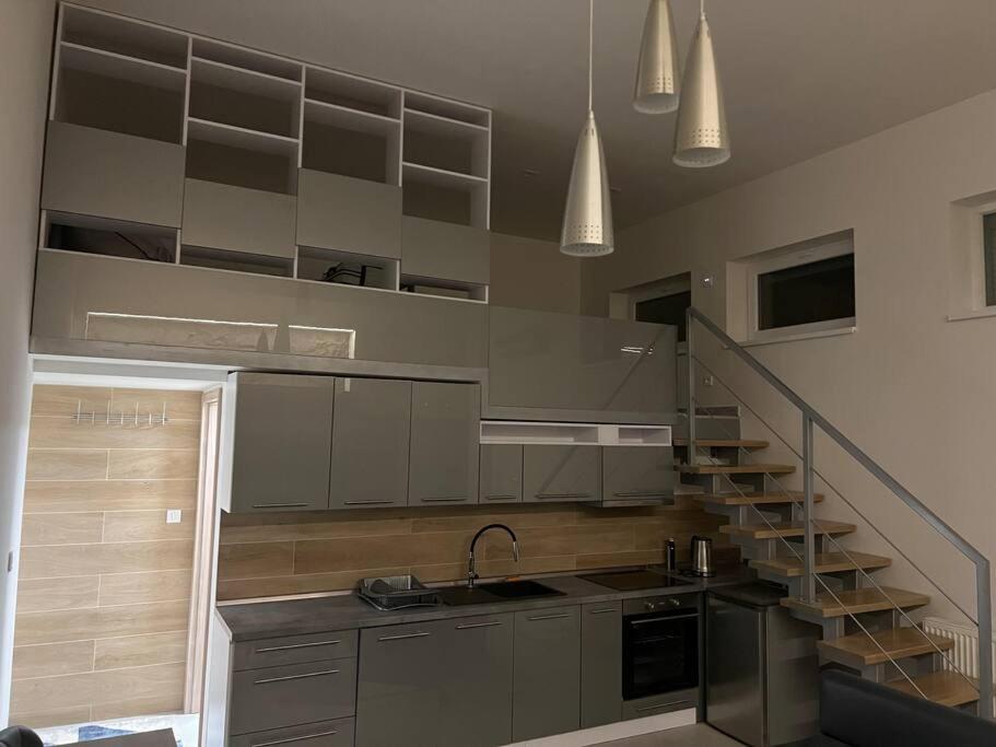 uma cozinha com uma escada, um lavatório e um balcão em Loft em Michalovce