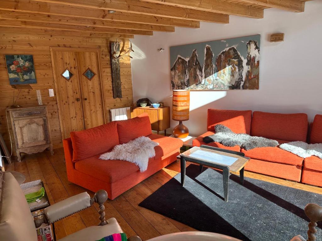 a living room with two orange couches and a table at Le Serre Barbin : Maison / Chalet avec jardin in Le Monêtier-les-Bains