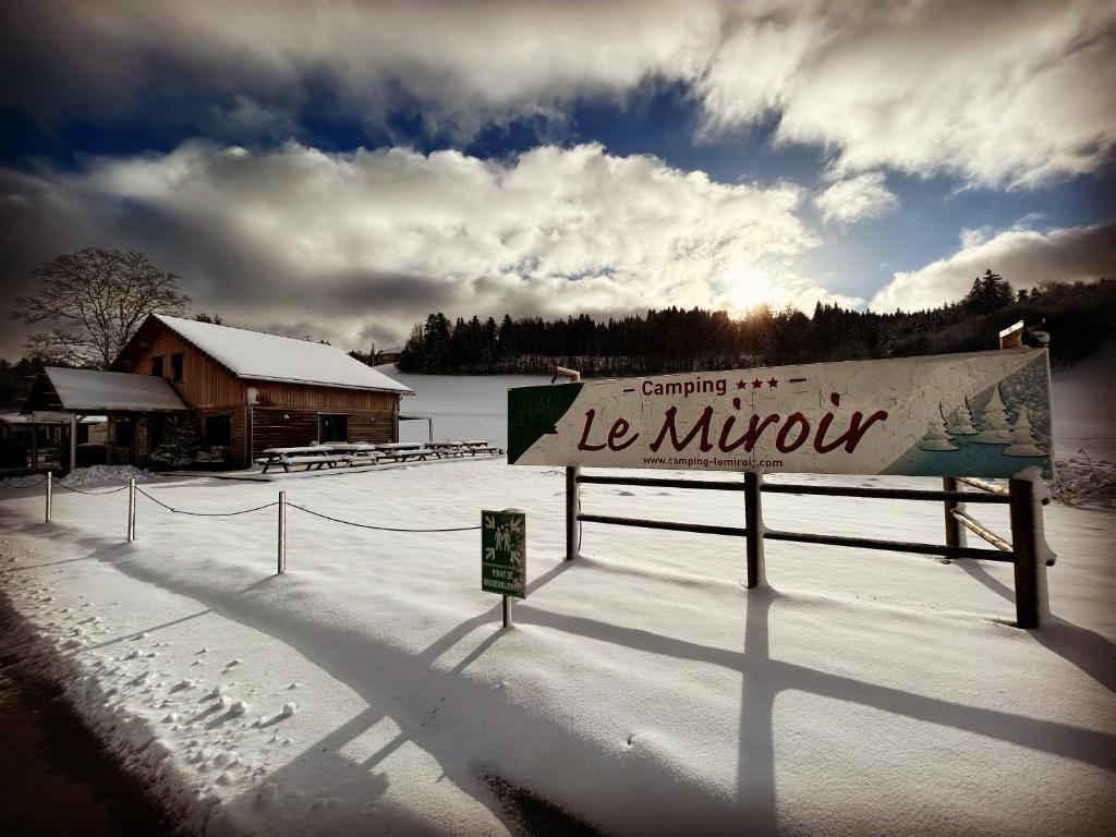 a sign in the snow in front of a building at Camping Le Miroir in Les Hôpitaux-Neufs