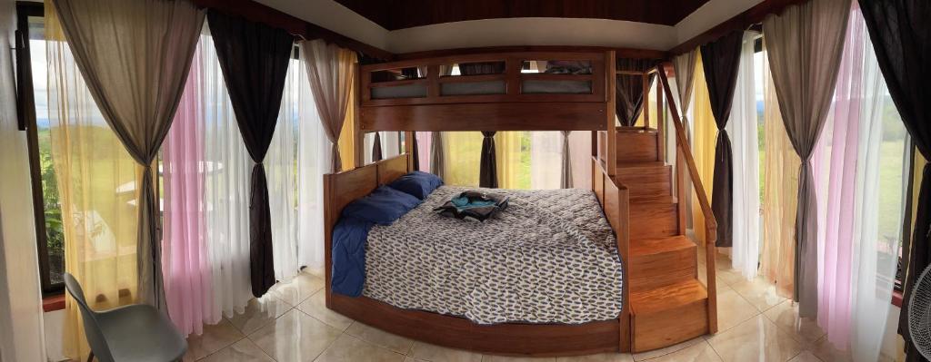 a bedroom with a canopy bed in a room with windows at Las Pavitas Cottages in Fortuna
