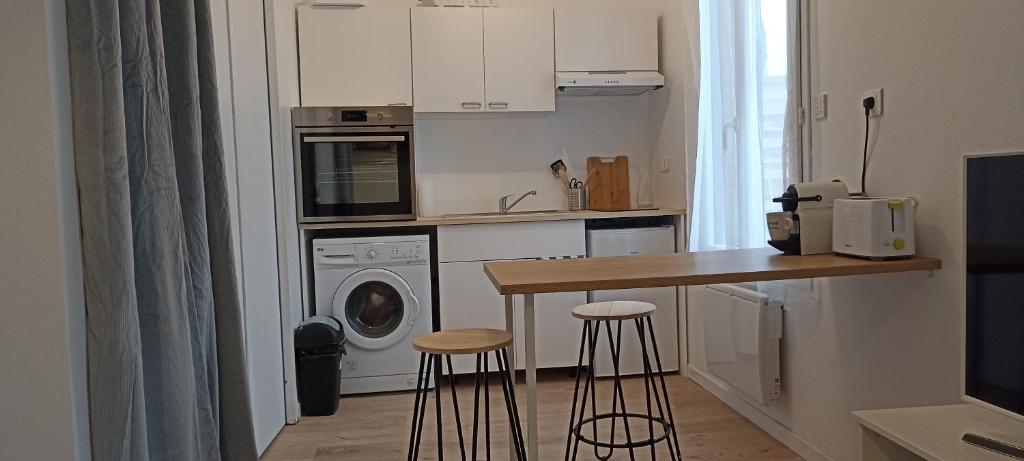 een keuken met een aanrecht en twee stoelen in een keuken bij Studio cosy avec terrasse et jardin in Floirac