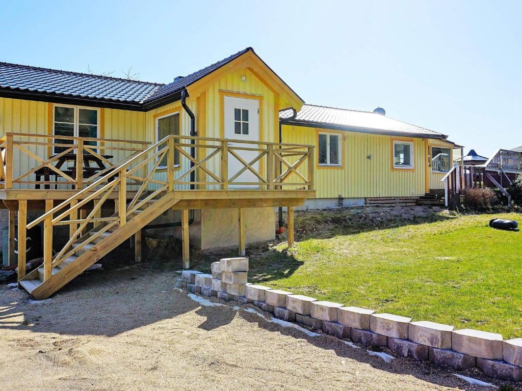 Holiday home SVANESUND IV في Svanesund: منزل أصفر مع شرفة وسطح