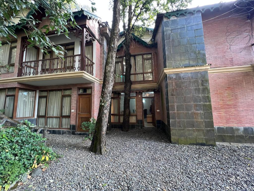 un edificio de ladrillo con un árbol delante de él en Villa Bliss Lake View, en Nainital