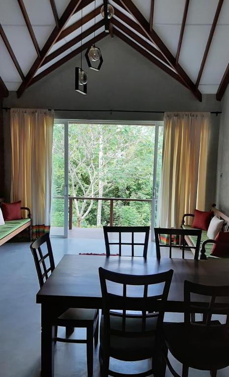 una sala da pranzo con tavolo, sedie e una grande finestra di Victoria Views Resort Kandy a Digana