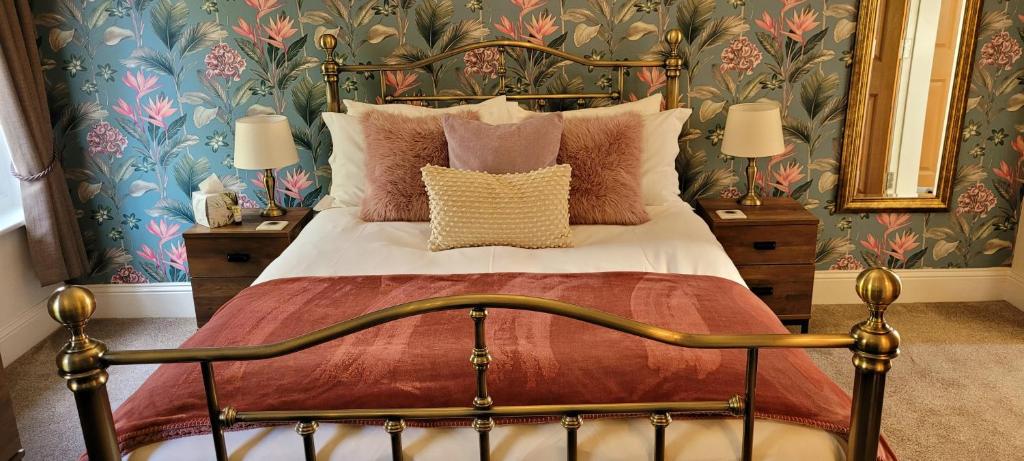 1 dormitorio con cama con almohadas y papel pintado con motivos florales en The Florence Guest House, en Whitby