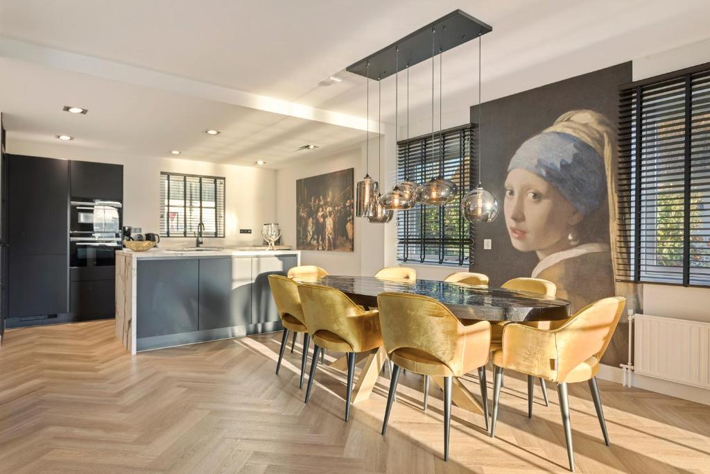 una cucina e una sala da pranzo con un dipinto di una donna di Villa Vermeer a Callantsoog