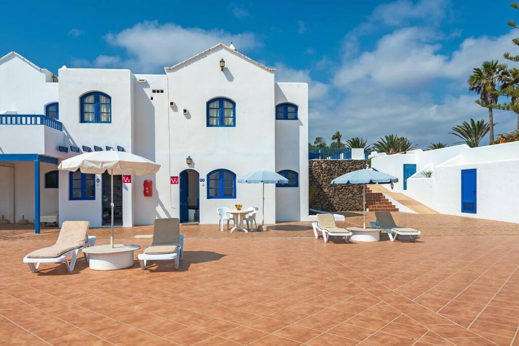 a group of chairs and umbrellas in front of a building at Precioso apartamento para nudistas y naturistas. in Charco del Palo