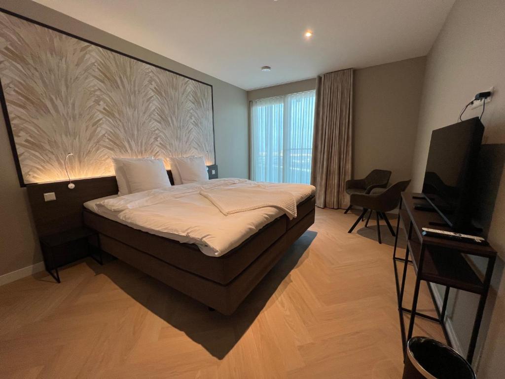 a bedroom with a bed and a flat screen tv at Residentie de Schelde - Apartments with hotel service and wellness in Cadzand-Bad