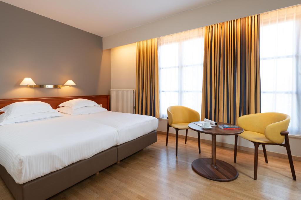 a hotel room with a bed and two chairs and a table at Rosenburg Hotel Brugge in Bruges