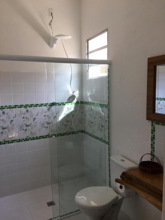 uma casa de banho com uma cabina de duche em vidro e um WC. em Recanto do Ipê em Extrema