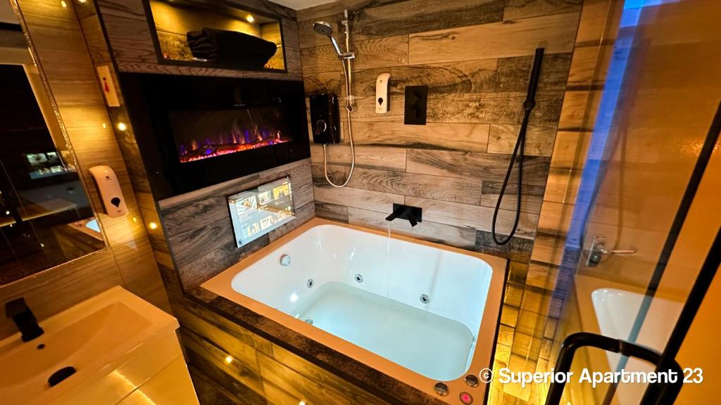 ein Bad mit einer Badewanne und einer Dusche sowie ein TV in der Unterkunft Serenity Apartments Bradford in Bradford