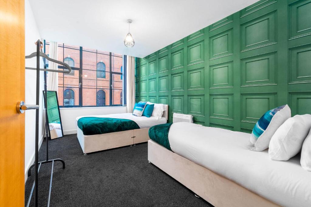 - 2 lits dans une chambre avec un mur vert dans l'établissement COSY Birmingham City Centre Spacious Apartment-Free parking, WiFi, Contractors, HS2, Bullring, Birmingham City FC, à Birmingham