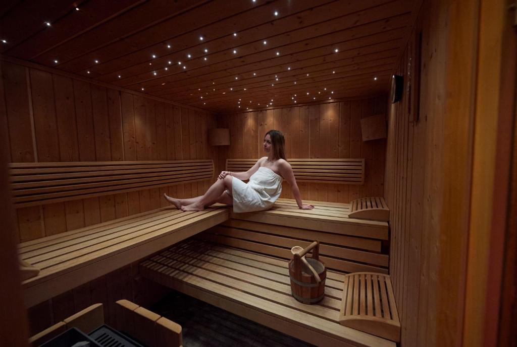 a woman is sitting in a sauna at Logis Hôtel et Spa Le Christiania in La Salle-les-Alpes