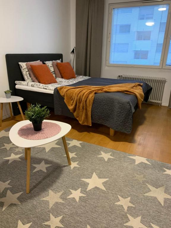 Schlafzimmer mit einem Bett, einem Tisch und einem Teppich in der Unterkunft StarHomes in Oulu