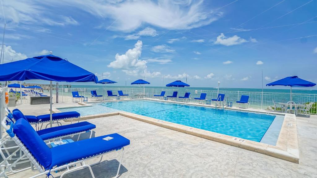 a swimming pool with blue chairs and umbrellas at Glunz Ocean Beach Hotel and Resort in Marathon