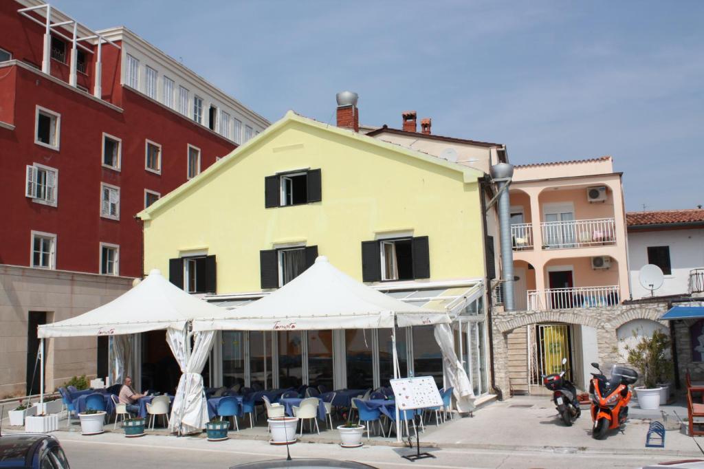 ein gelbes Gebäude mit einem Zelt vor einem Gebäude in der Unterkunft Apartments Tomato in Novigrad Istria