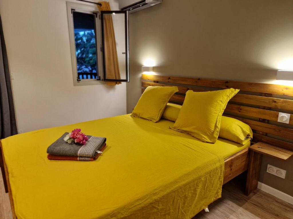 a yellow bed with a wooden headboard and yellow pillows at Appartement les petits Baobabs in Mamoudzou