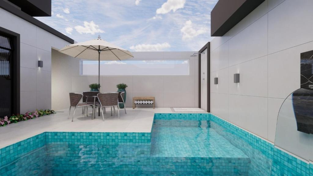 a house with a swimming pool with a table and an umbrella at Uma Quadra do MAR Com PISCINA, Churrasqueira, 2 Vg de Garagem e 3 Quartos!!! in Praia Grande