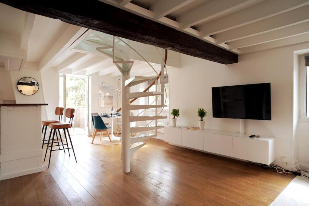 sala de estar con escalera de caracol y TV en Duplex de charme avec terrasse aux portes de Paris, en Saint-Germain-en-Laye