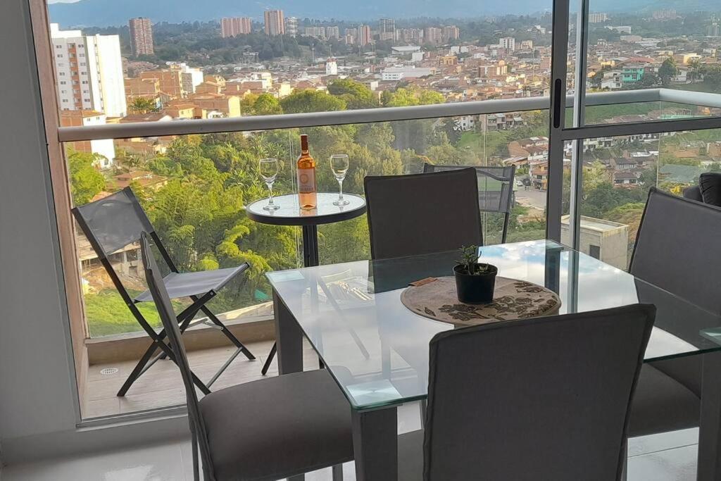a table and chairs with a bottle of wine on a balcony at Rionegro, Apto Moderno Campestre, cerca aeropuerto in Rionegro
