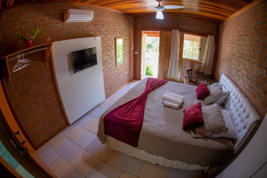 ein Schlafzimmer mit einem großen Bett in einer Ziegelwand in der Unterkunft Chalés Sapucaí Pousada in São Bento do Sapucaí