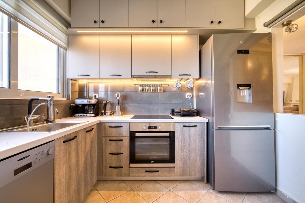 een keuken met witte kasten en een roestvrijstalen koelkast bij Sea & Mountain Apartment Close to Port and City in Lávrion