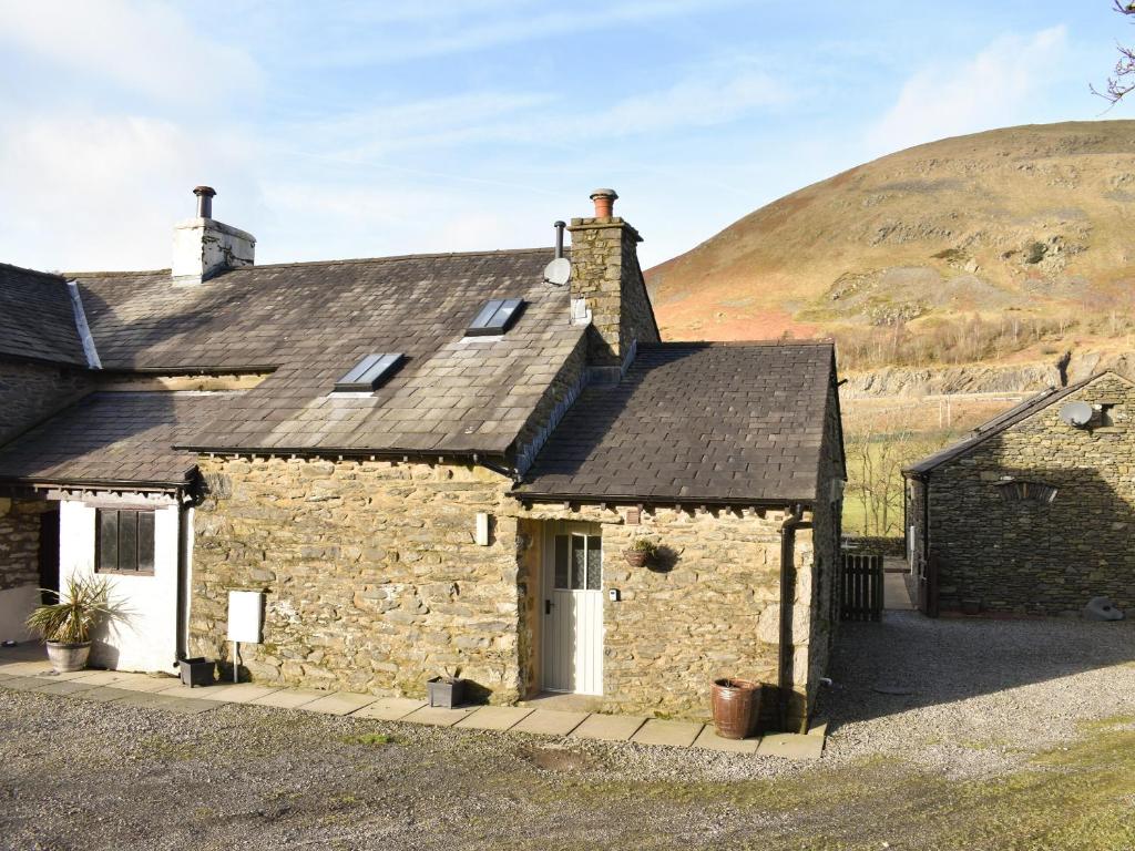 een oud stenen huisje met een heuvel op de achtergrond bij Oaktree Cottage-uk42227 in Low Borrowbridge