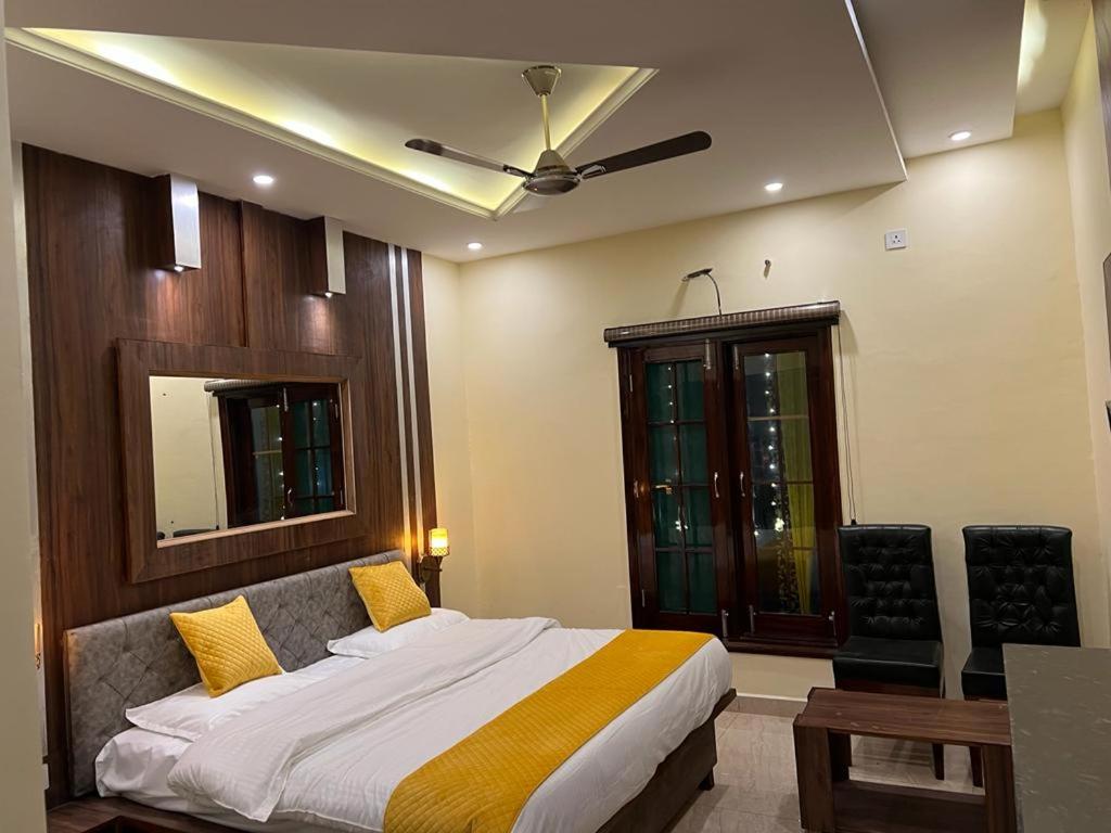 Hotel Sukoon Bharatgarh في Rūpnagar: غرفة نوم بسرير ومروحة سقف