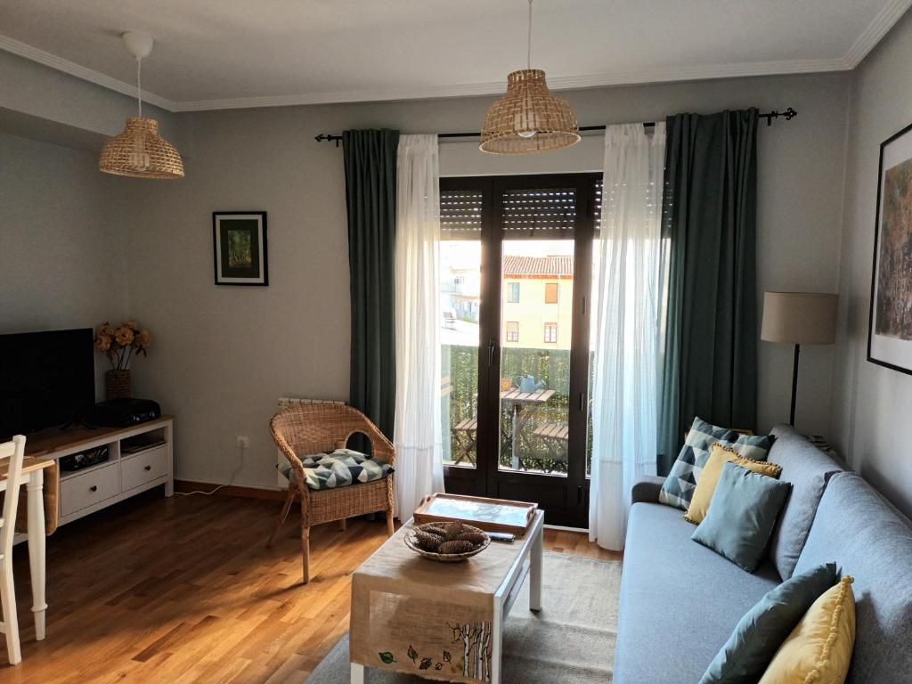 sala de estar con sofá azul y ventana en La casa de los abedules en León