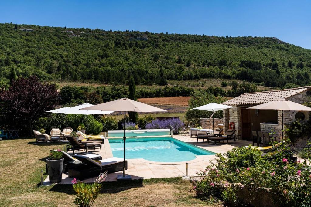 a swimming pool with chairs and umbrellas in a yard at Mon Ventoux - Cozyhotes in Sault-de-Vaucluse