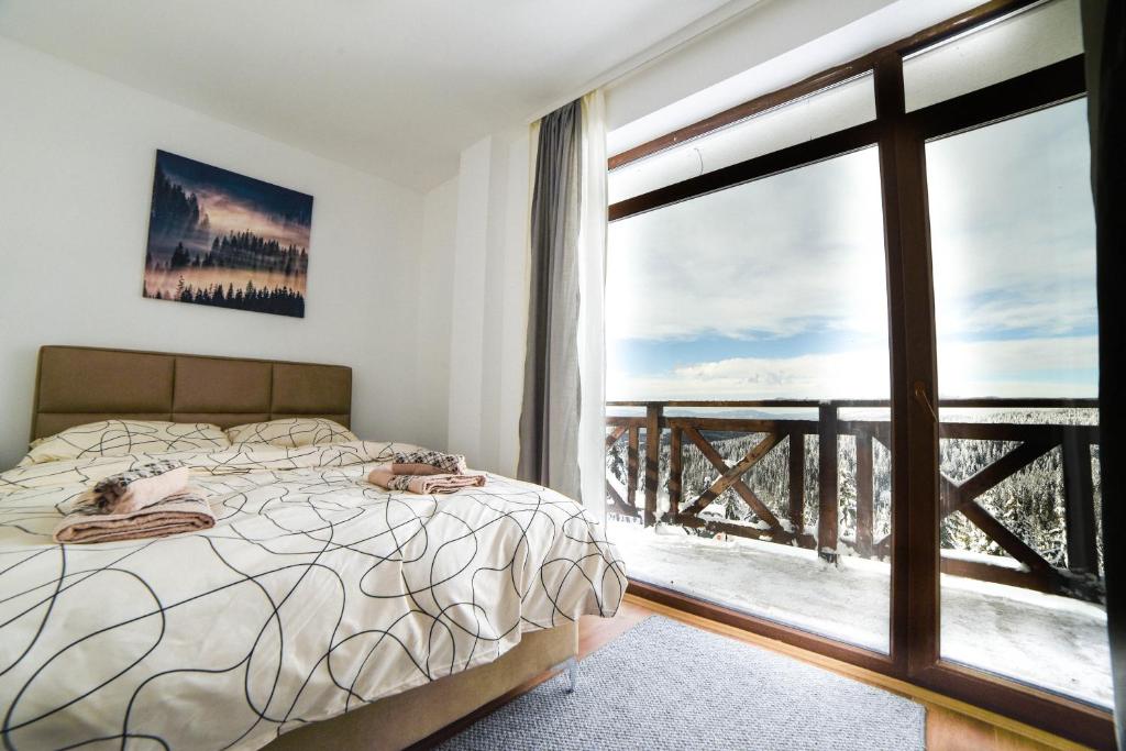 a bedroom with a bed and a large window at Apartman La Foresta Kopaonik in Kopaonik