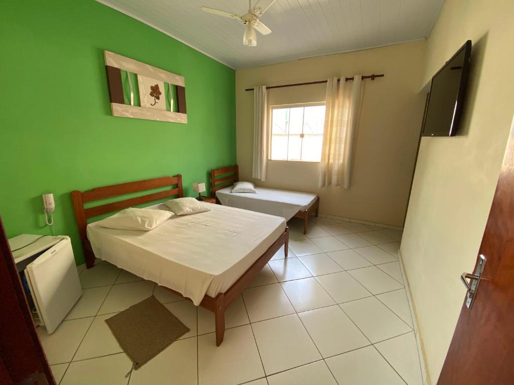 a bedroom with a bed and a green wall at Hotel Modelo in Poços de Caldas