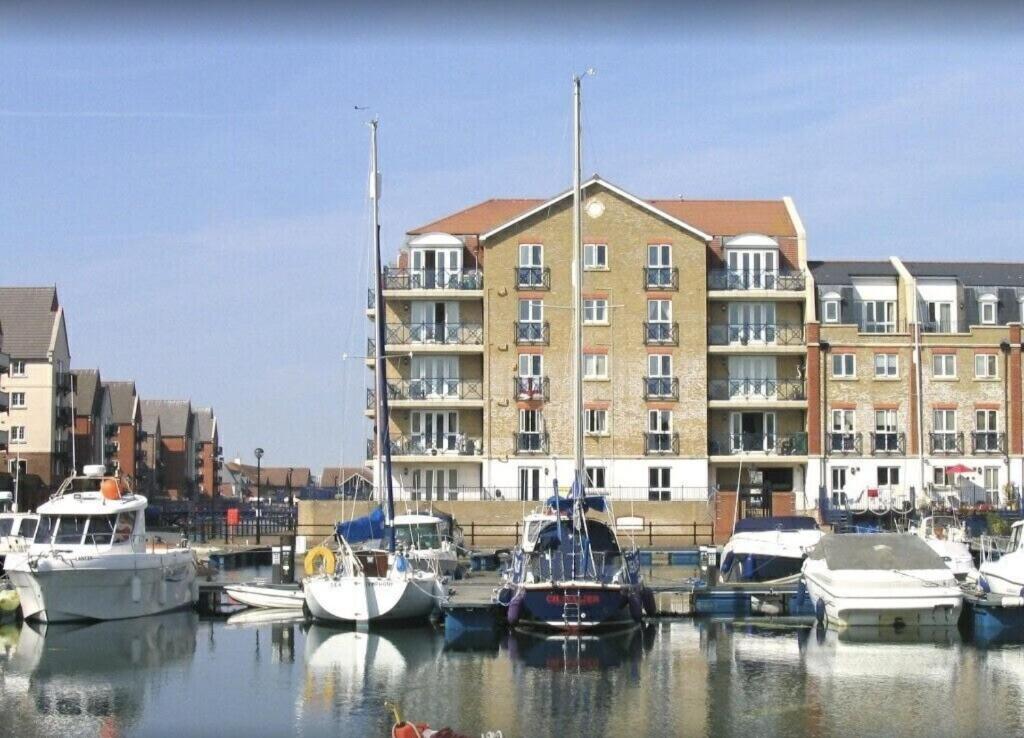 un grupo de barcos atracados en un puerto deportivo con un edificio en Fabulously located Marina apartment - marina views, en Pevensey